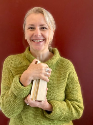 Portrait de l'autrice Cécile Roumiguière avec des livres dans les mains